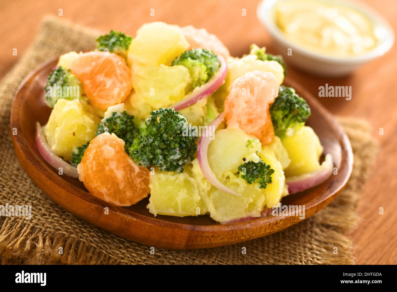La pomme de terre fraîche, le brocoli, le mandarin et l'oignon salade avec mayonnaise sur plaque de bois Banque D'Images