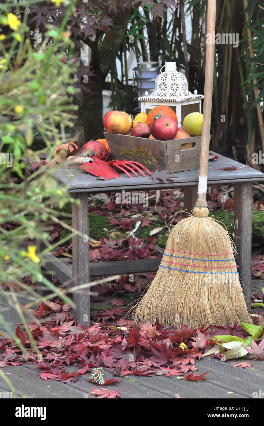 La collecte des feuilles sur une terrasse en bois à l'automne Banque D'Images