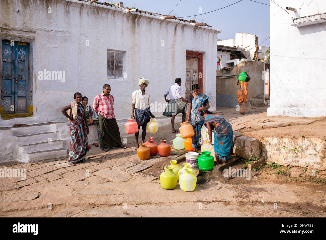 Les femmes indiennes le remplissage des pots en plastique avec de l'eau d'un tube de mesure dans une rue village. L'Andhra Pradesh, Inde Banque D'Images