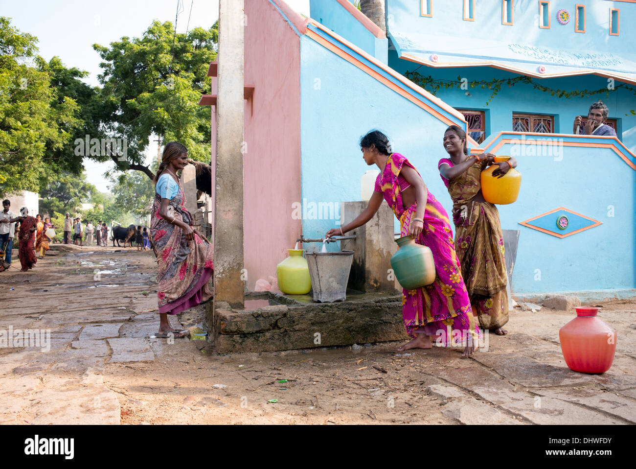 Les femmes indiennes le remplissage des pots en plastique avec de l'eau d'un tube de mesure dans une rue village. L'Andhra Pradesh, Inde Banque D'Images