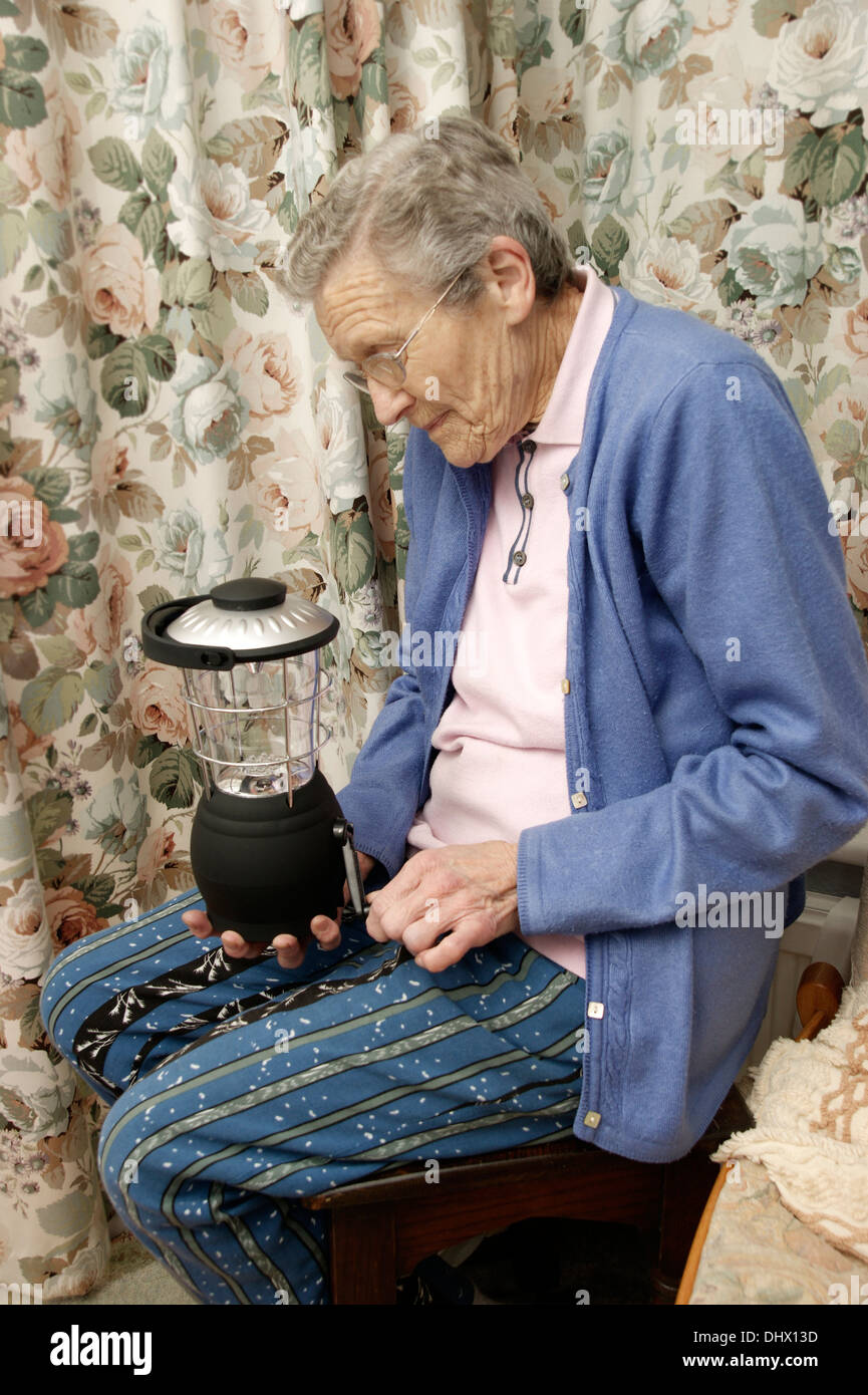 Femme âgée liquidation liquidation lantern utilisé comme éclairage d'urgence pour les pannes d'électricité et à court d'électricité Banque D'Images