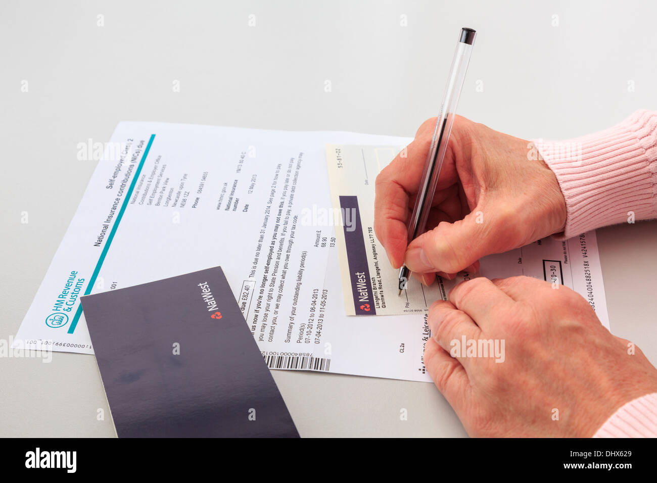 Femme mature l'écriture d'un Nat West chèque bancaire à payer pour un projet de loi pour les travailleurs autonomes de classe 2 à l'Assurance nationale au Royaume-Uni Banque D'Images