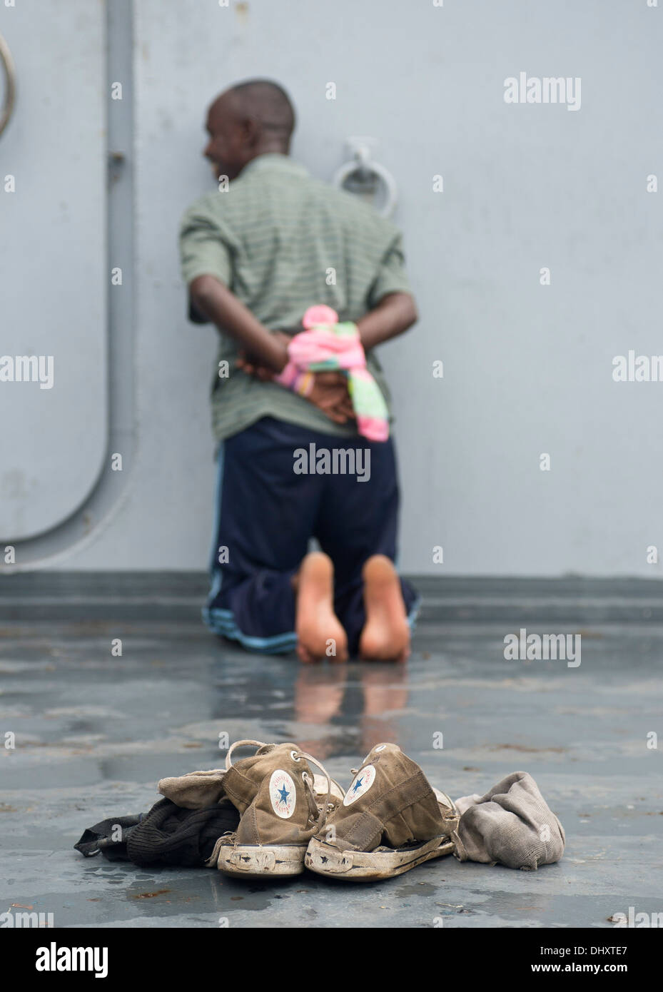 DJIBOUTI, Djibouti (nov. 14, 2013) - La simulation d'un détenu doit attendre après une fouille à bord d'un navire cible pendant l'exercice 2013 dans l'Express Cutlass Golfe de Tadjourah près de Djibouti. Exercice Cutlass Express 2013 est un exercice maritime multinational en t Banque D'Images