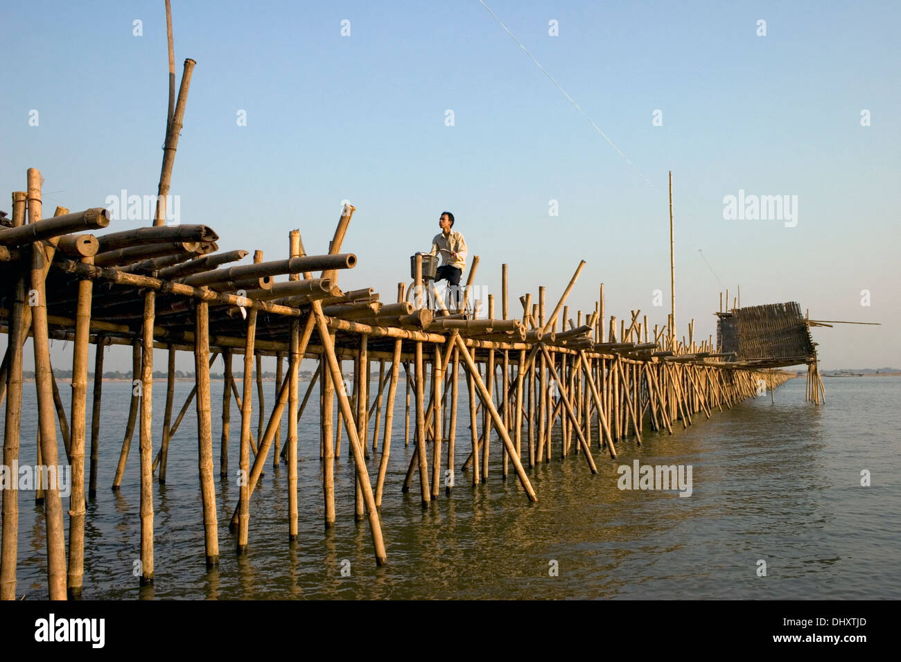 Un homme est en train de rouler à vélo sur un pont de bambou sur la rivière du Mékong à Kampong Cham, au Cambodge. Banque D'Images