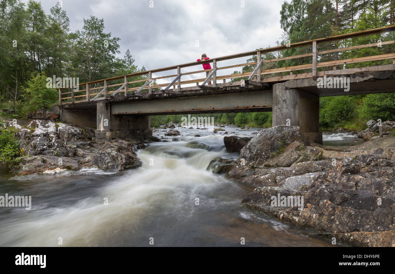Jeune fille regarde l'eau coule sous un pont dans les Highlands écossais Banque D'Images