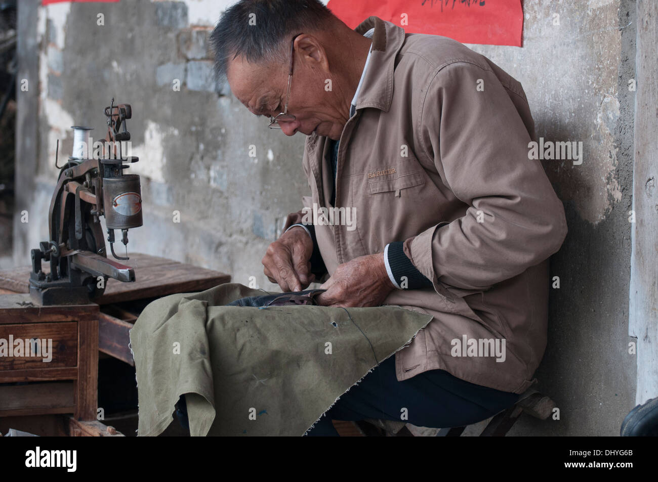 Réparateur de chaussures à l'œuvre dans l'heritage village de Tangmo, Huizhou, Anhui, Chine Banque D'Images
