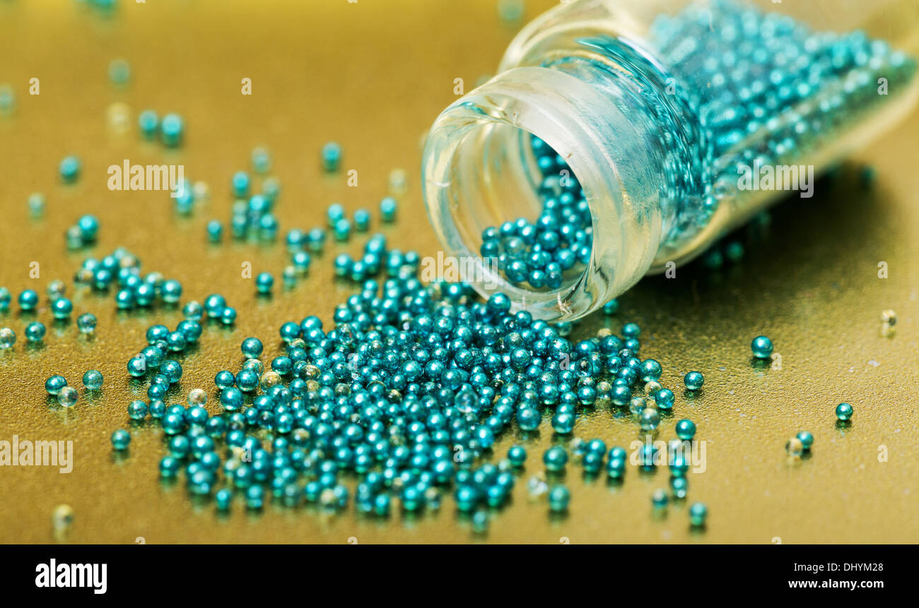 Petit bocal en verre rempli de boules vertes de colle, sur fond doré Banque D'Images