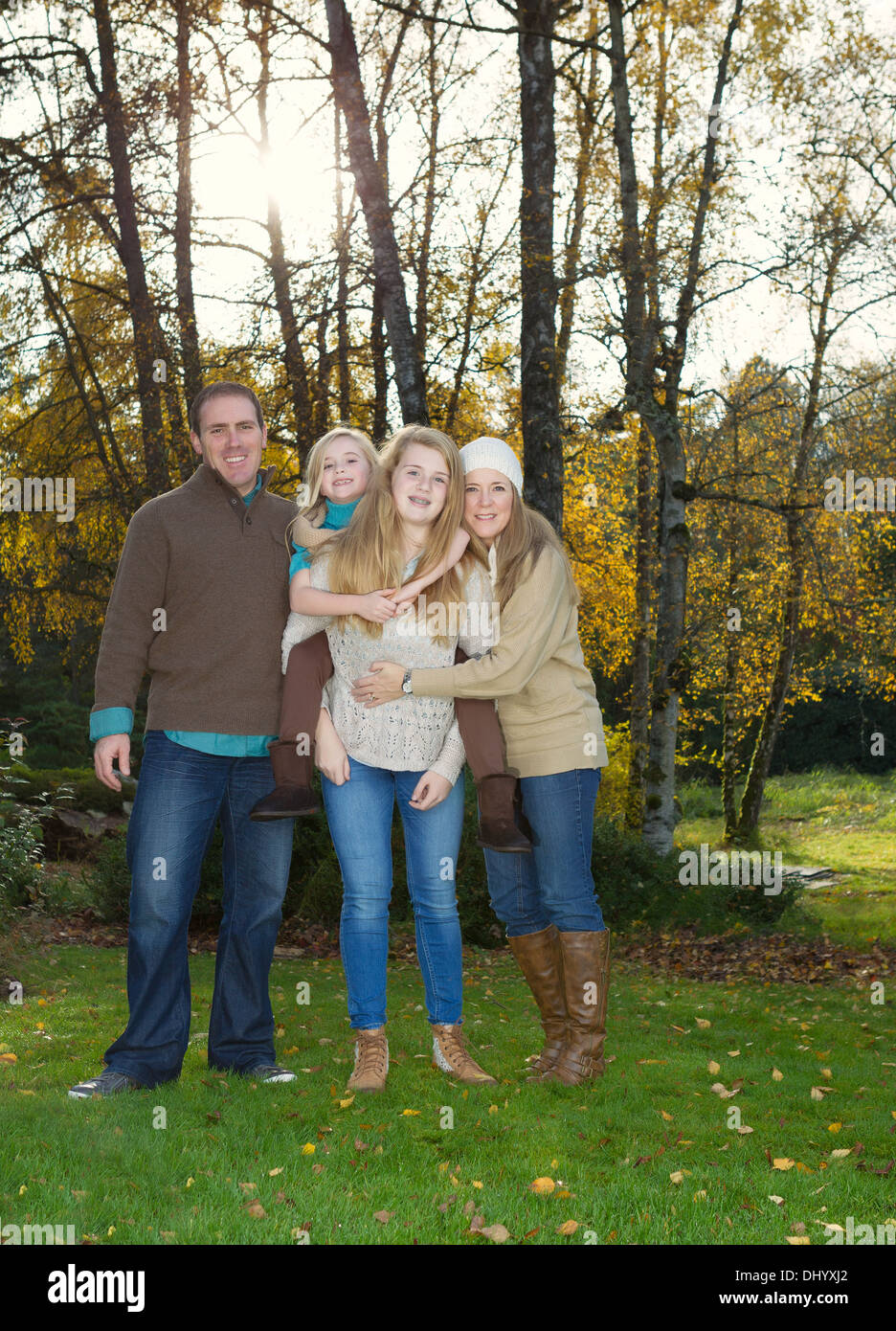 Photo de famille verticale debout devant des arbres, avec la lumière du soleil qui à travers, par une belle journée dans la saison d'automne Banque D'Images