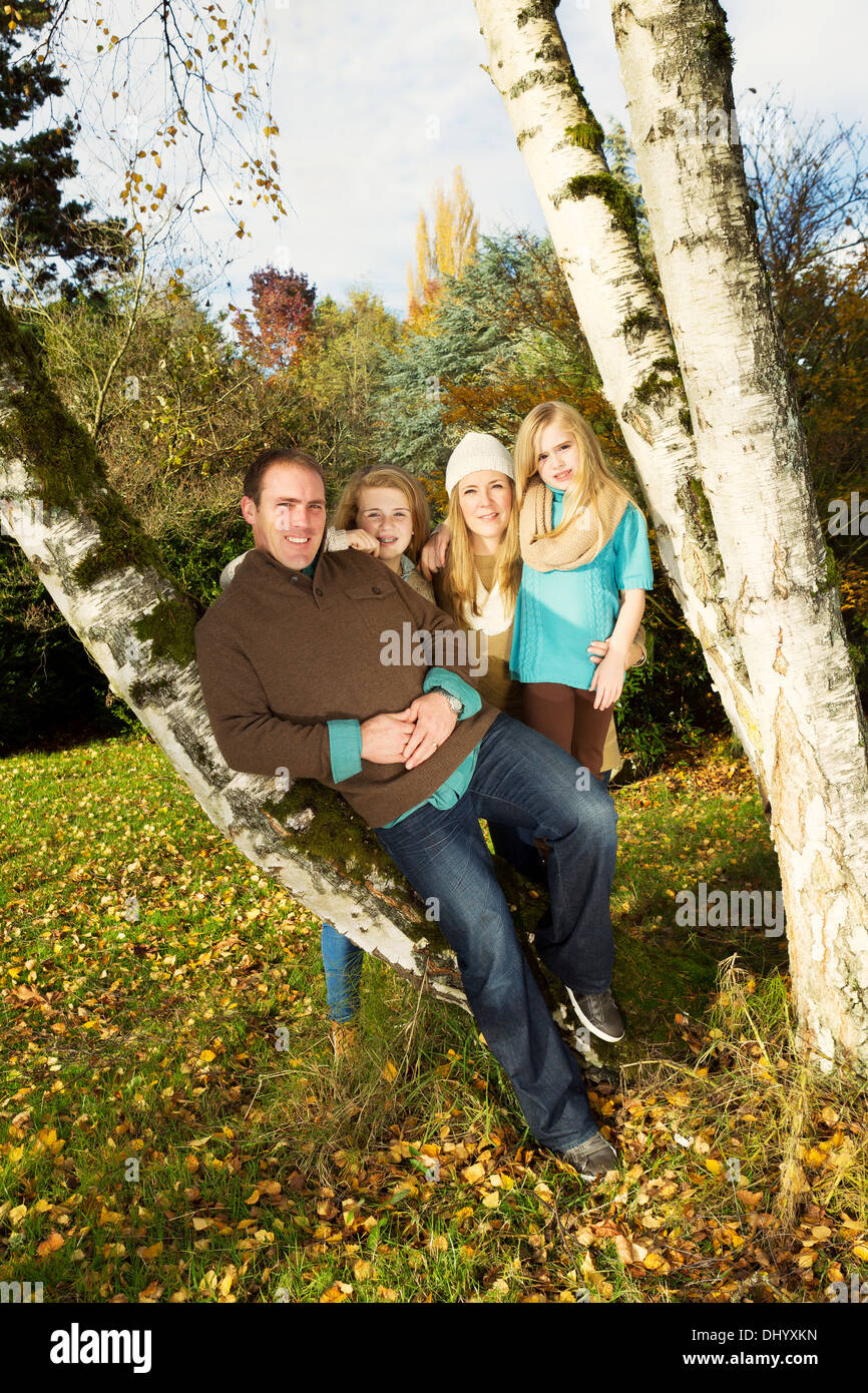 Photo de famille verticale reposant sur les arbres, avec l'homme en avant-garde, au cours d'une journée agréable en automne Banque D'Images