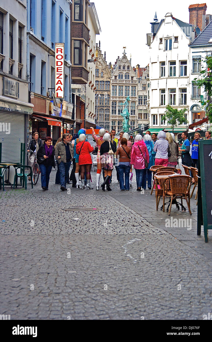 Un groupe de personnes en perruques et blanc boots marche vers la Grand-place d'Anvers en tant que spectateurs à pied par et observer. Banque D'Images