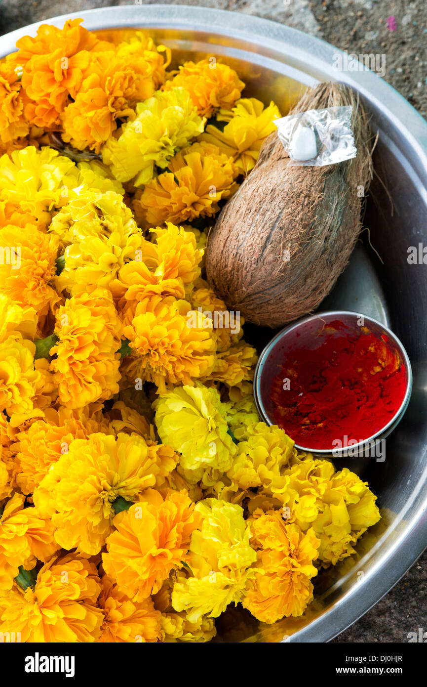 Bol en métal contenant des fleurs de souci indiennes, la noix de coco et kum kum poudre pour une puja hindoue en Inde Banque D'Images