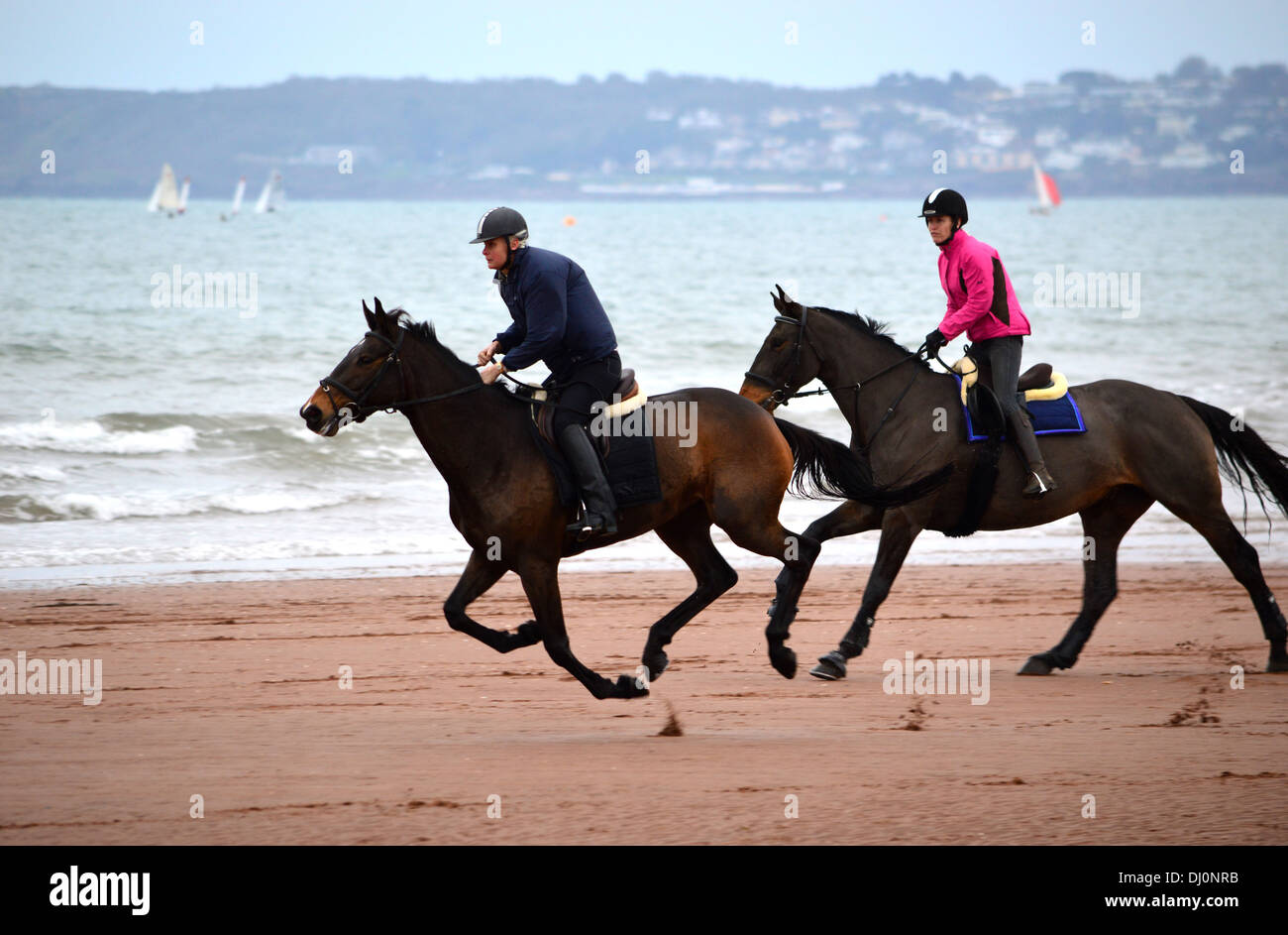 Deux cavaliers sur la plage de Paignton, Torbay, dans le Devon, Angleterre, Royaume-Uni Banque D'Images
