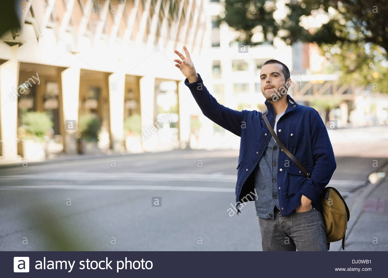 Homme hailing taxi on city street Banque D'Images