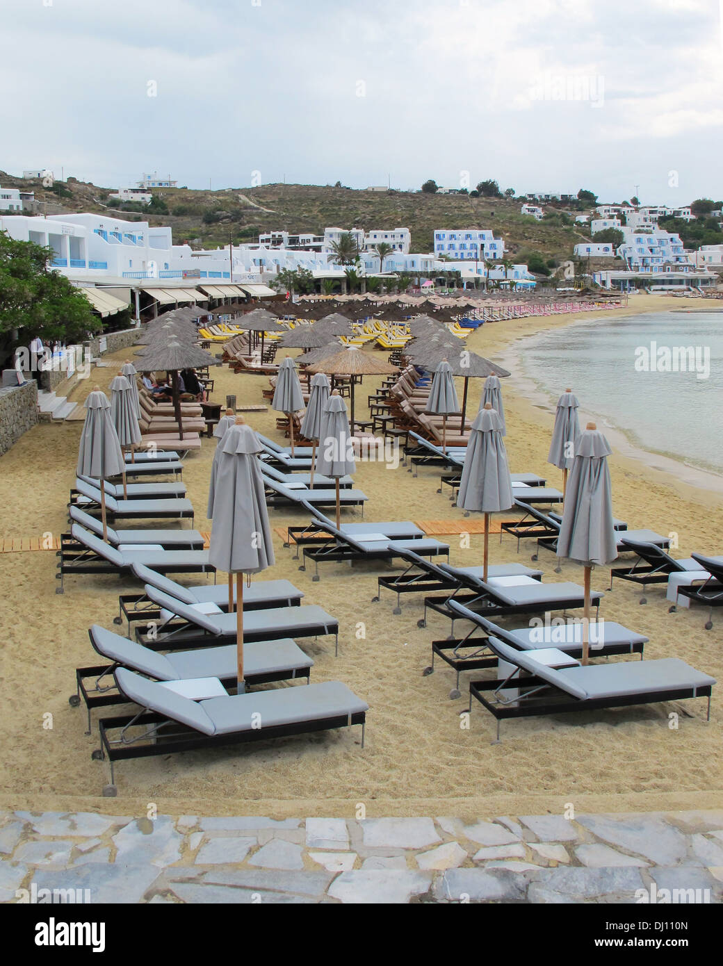 Des chaises longues et des parasols sur la plage de Platys Gialos, sur l'île grecque de Mykonos dans les Cyclades Banque D'Images