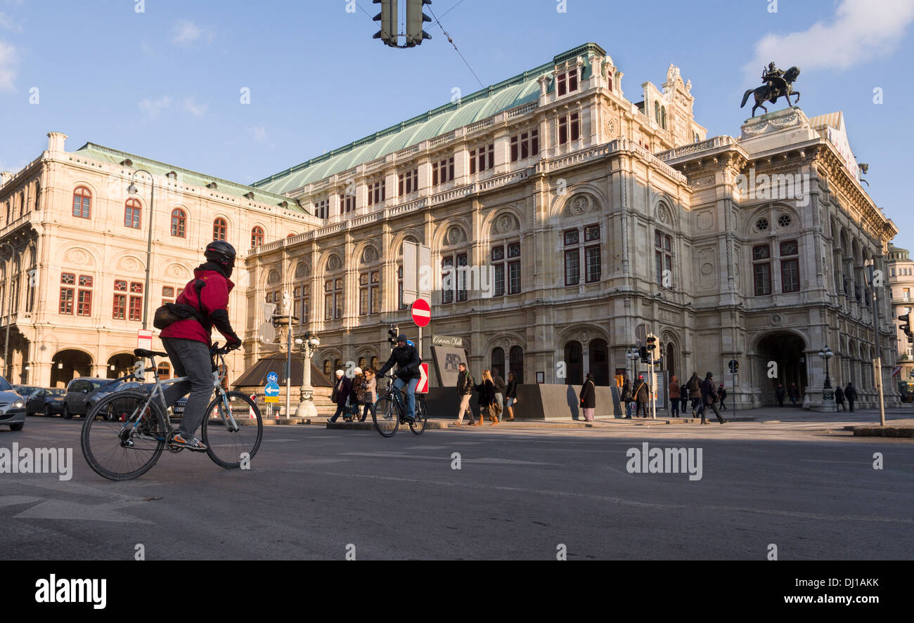 Opéra de Vienne et les cyclistes. Un cycliste traverse la rue en face de l'Opéra de Vienne massive. Banque D'Images