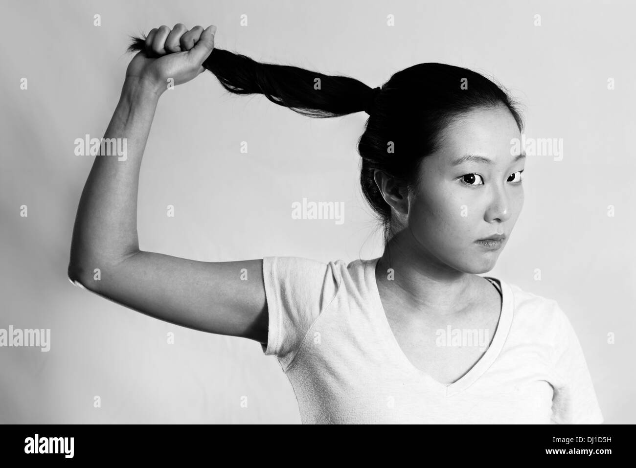 Portrait de jeune femme solitaire tirant ses cheveux à la frustrée, style noir et blanc Banque D'Images