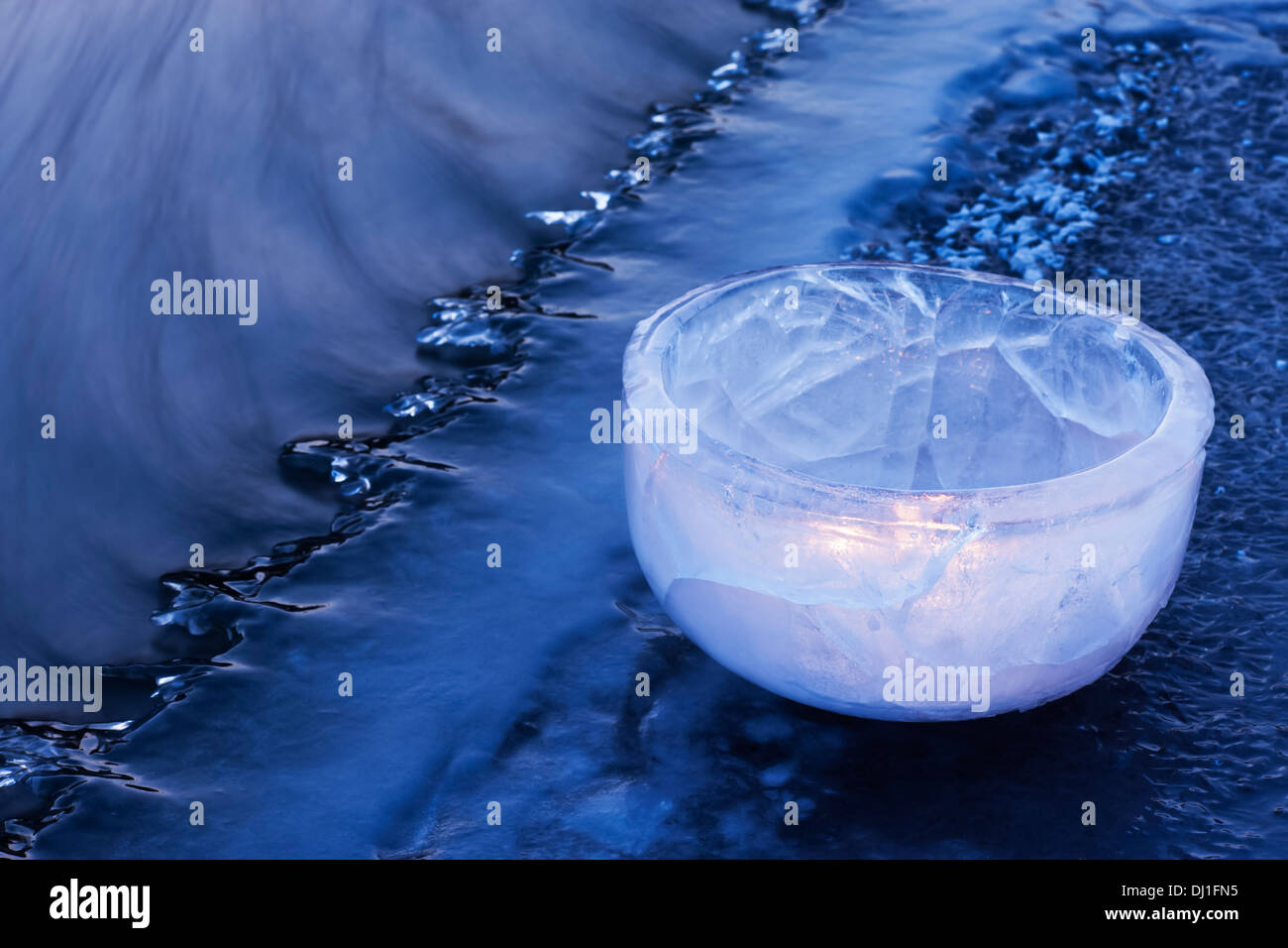 Bol lumineux fait de glace, placé sur une rivière, jusqu'figées à l'heure bleue Banque D'Images