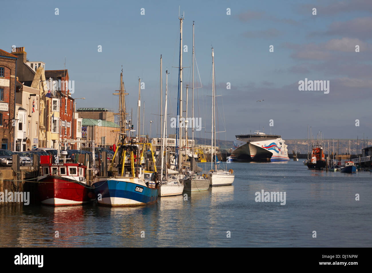 Des bateaux amarrés le long du port de Weymouth, au quai de Weymouth, avec le ferry Condor Express au loin à Weymouth, Dorset, Royaume-Uni, en novembre Banque D'Images