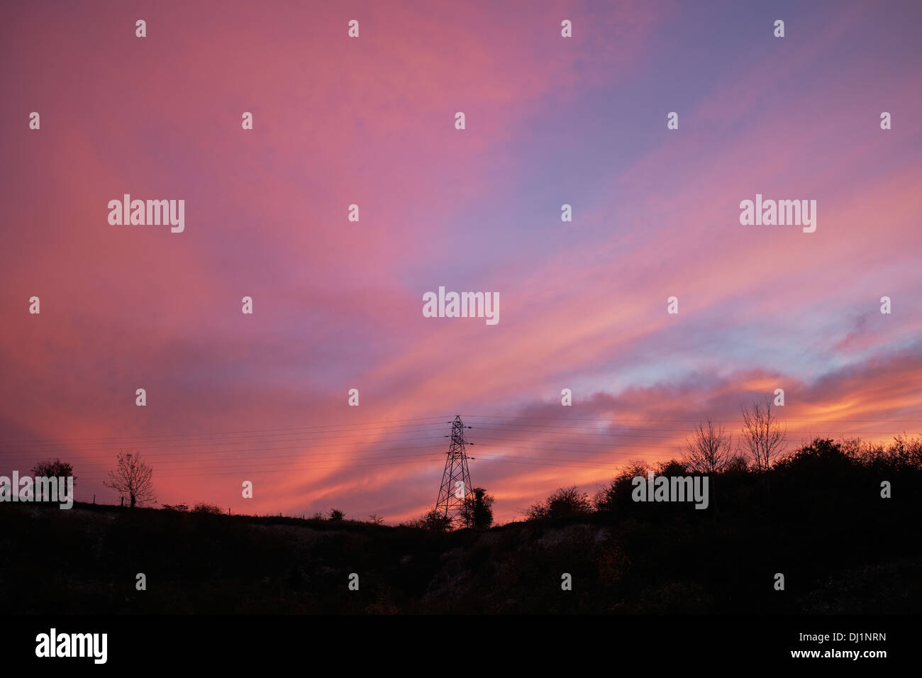 Coucher de soleil rouge derrière un pylône d'électricité Banque D'Images