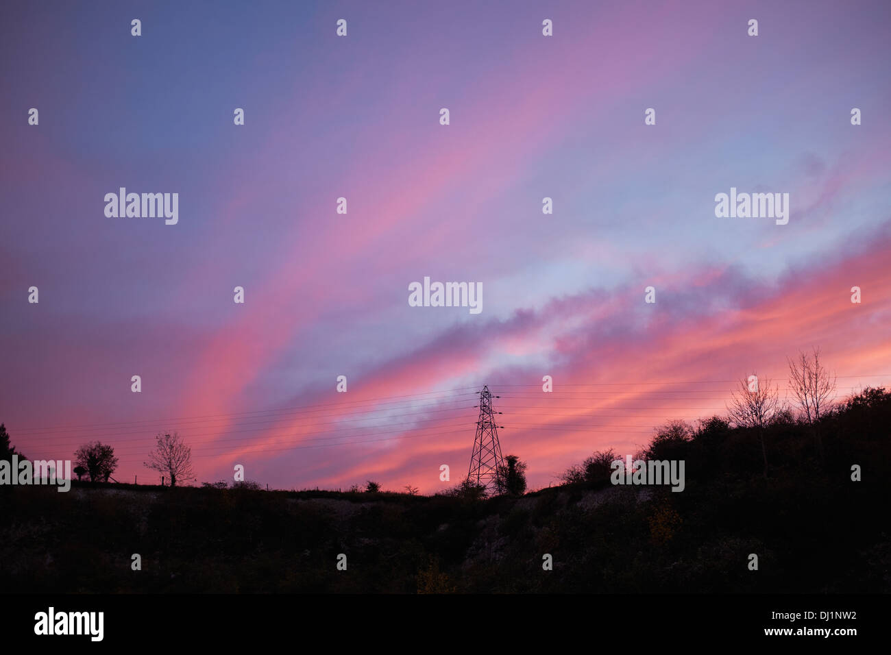 Coucher de soleil rouge derrière un pylône d'électricité Banque D'Images