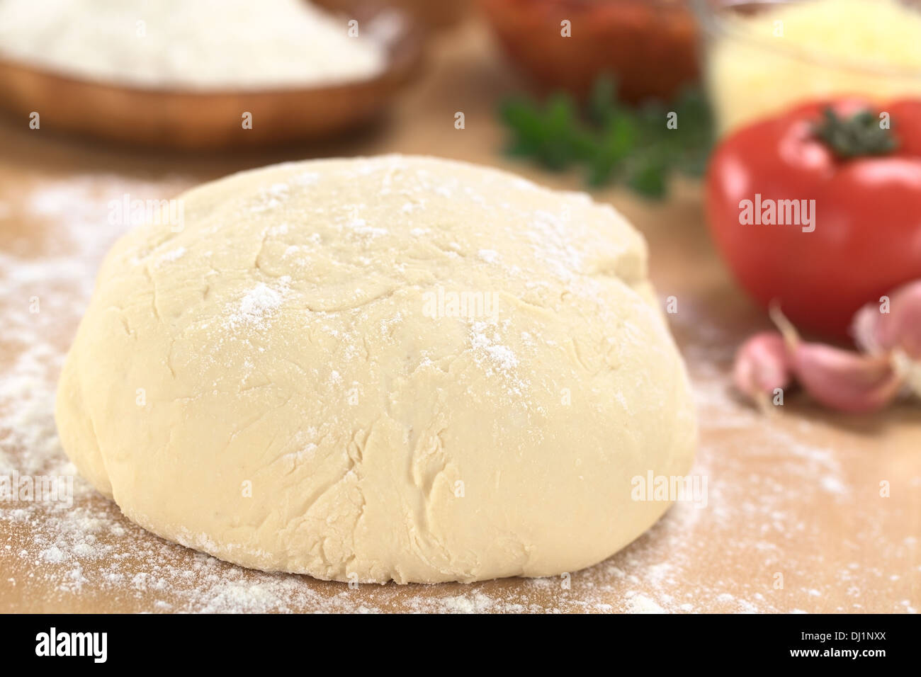 Pâte à pizza maison sur planche en bois farinée avec pizza ingrédients (farine, tomate, fromage râpé et d'herbes) dans l'arrière Banque D'Images