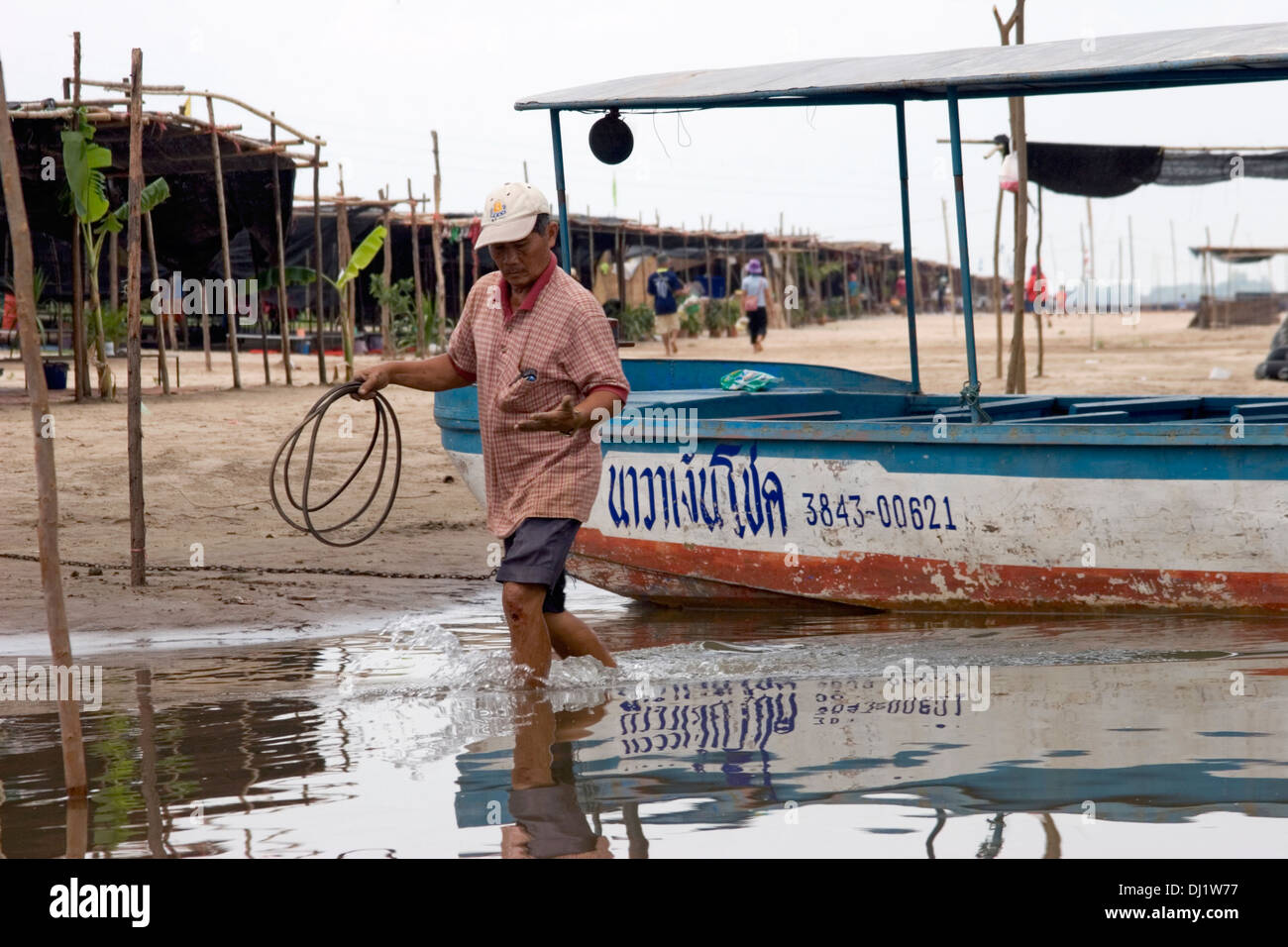 Un conducteur de bateau marche dans l'eau près des rives du Mékong dans Nong Khai, Thaïlande (Kai). Banque D'Images