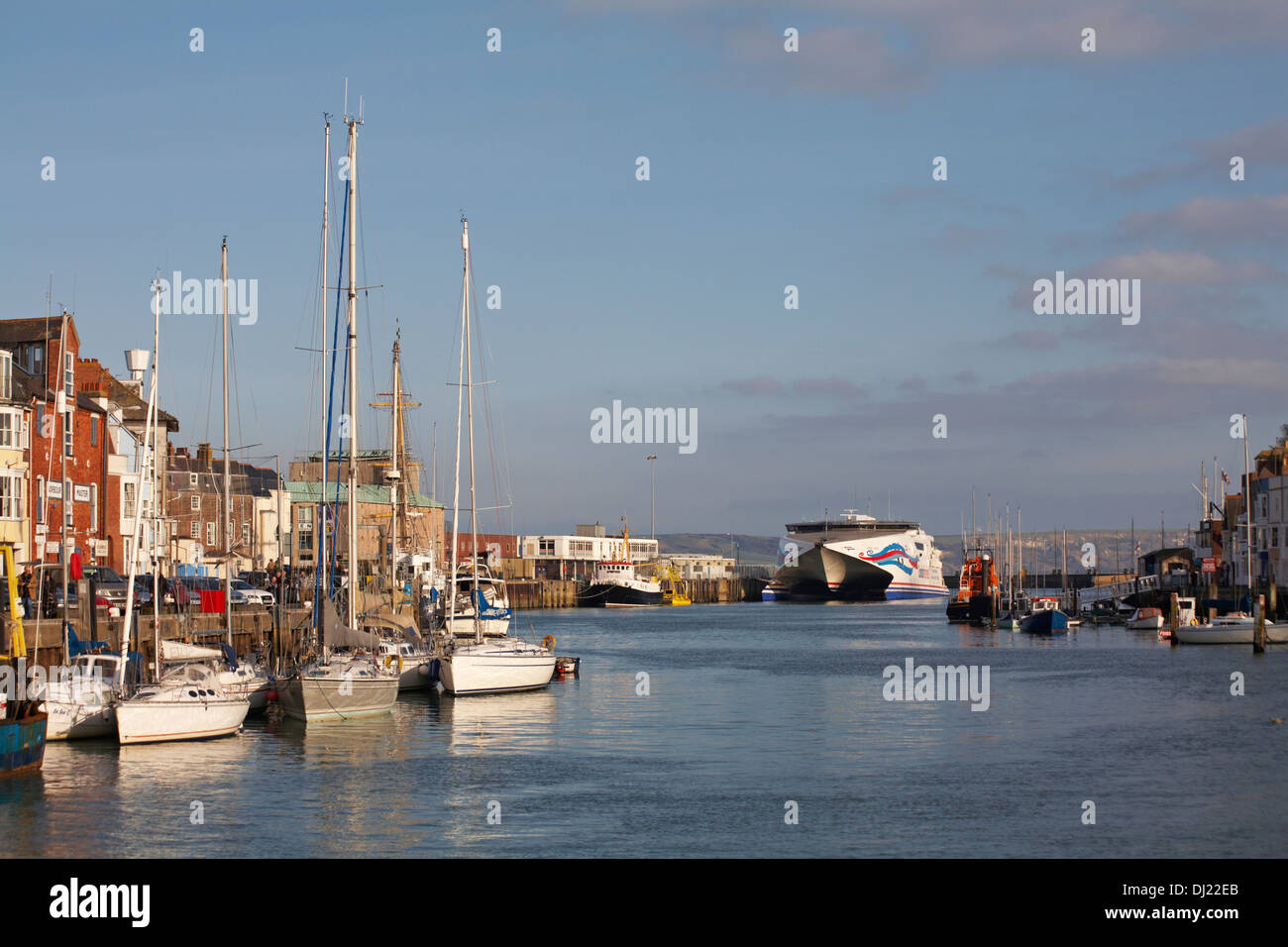 Des bateaux amarrés le long du port de Weymouth, au quai de Weymouth, avec le ferry Condor Express au loin à Weymouth, Dorset, Royaume-Uni, en novembre Banque D'Images