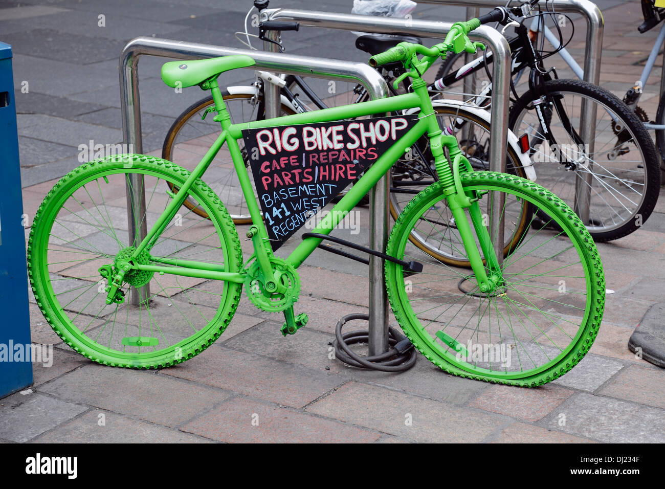 Un vélo peint en vert et avec un signe d'Age publicité Bike Shop, Glasgow, Écosse, Royaume-Uni Banque D'Images