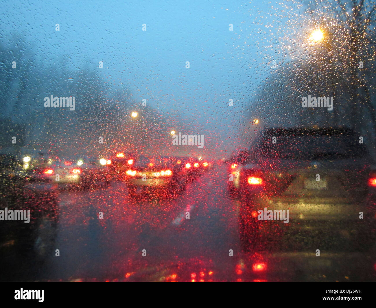 La conduite sur une route au crépuscule à l'heure de pointe avec de la pluie et de la brume sur le pare-brise. Banque D'Images