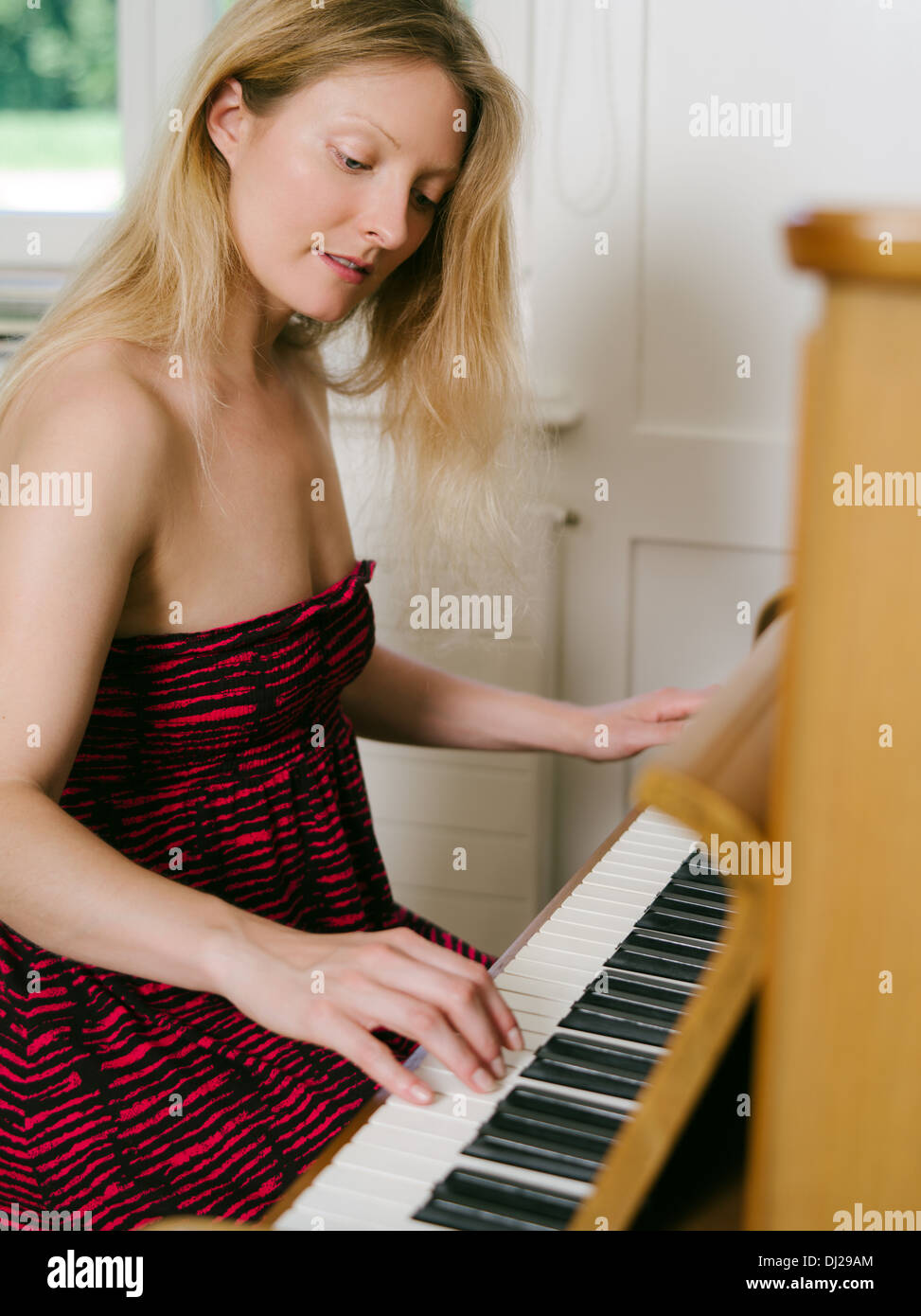 Photo d'une bonne blonde dans la trentaine de jouer du piano à la maison. Banque D'Images