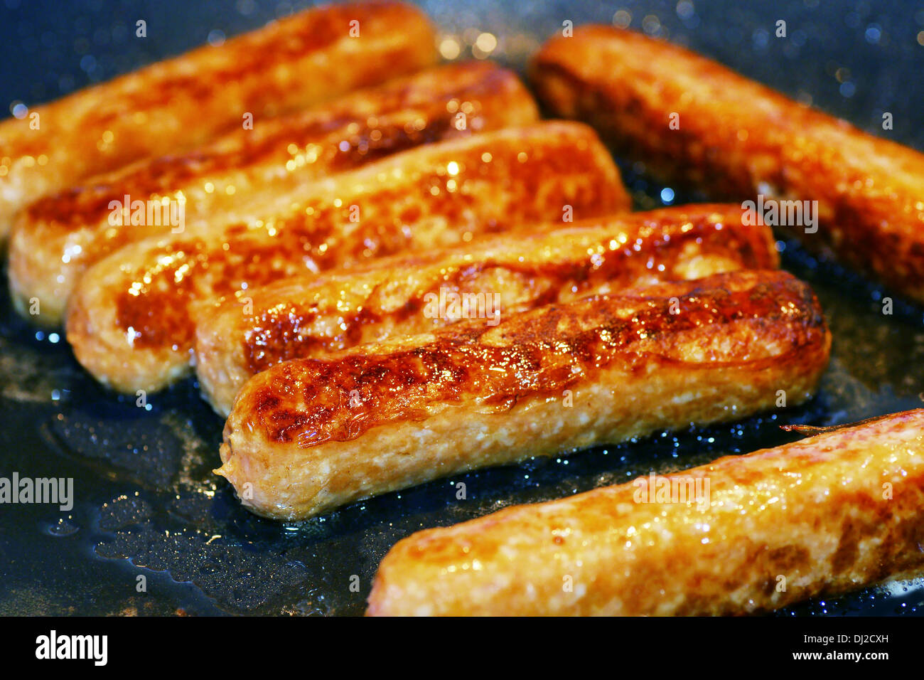 Saucisses de porc et de boeuf cuit dans une poêle avec de l'huile Banque D'Images