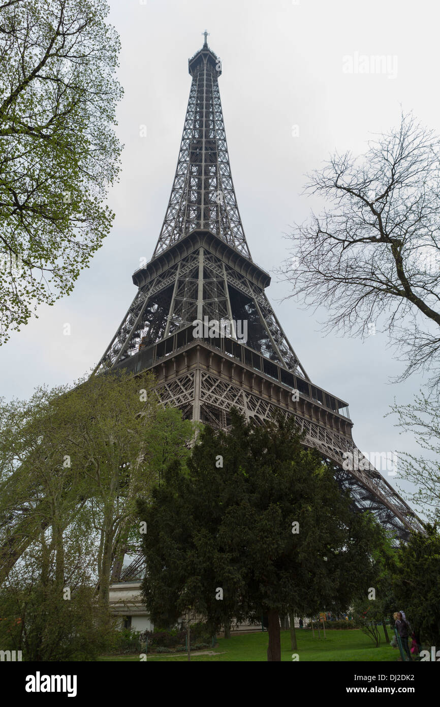 La Tour Eiffel à Paris, France sur une journée nuageuse tourné à l'angle à travers les arbres. Banque D'Images