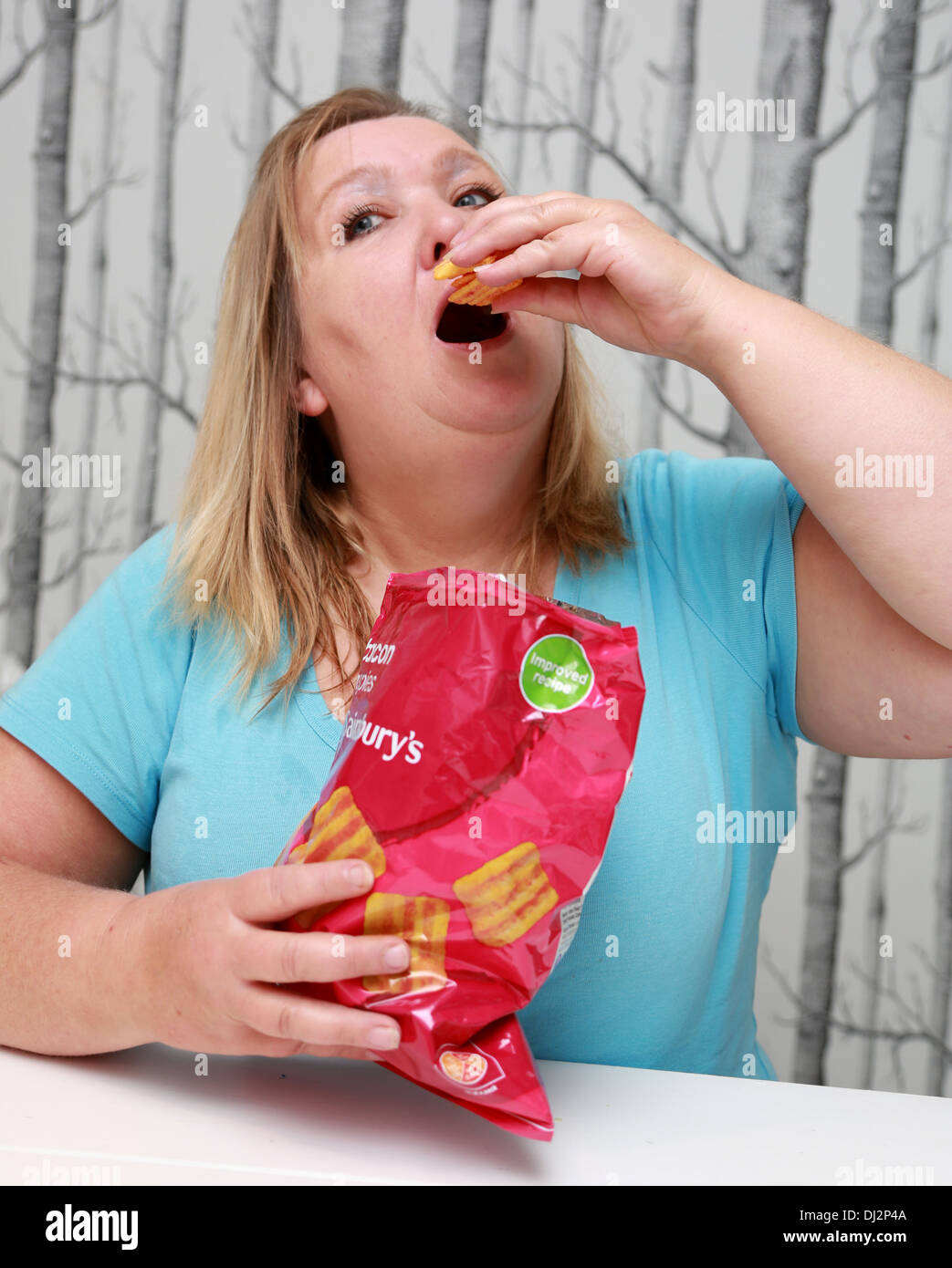 L'excès de femme de manger un sac de chips de taille familiale. Banque D'Images