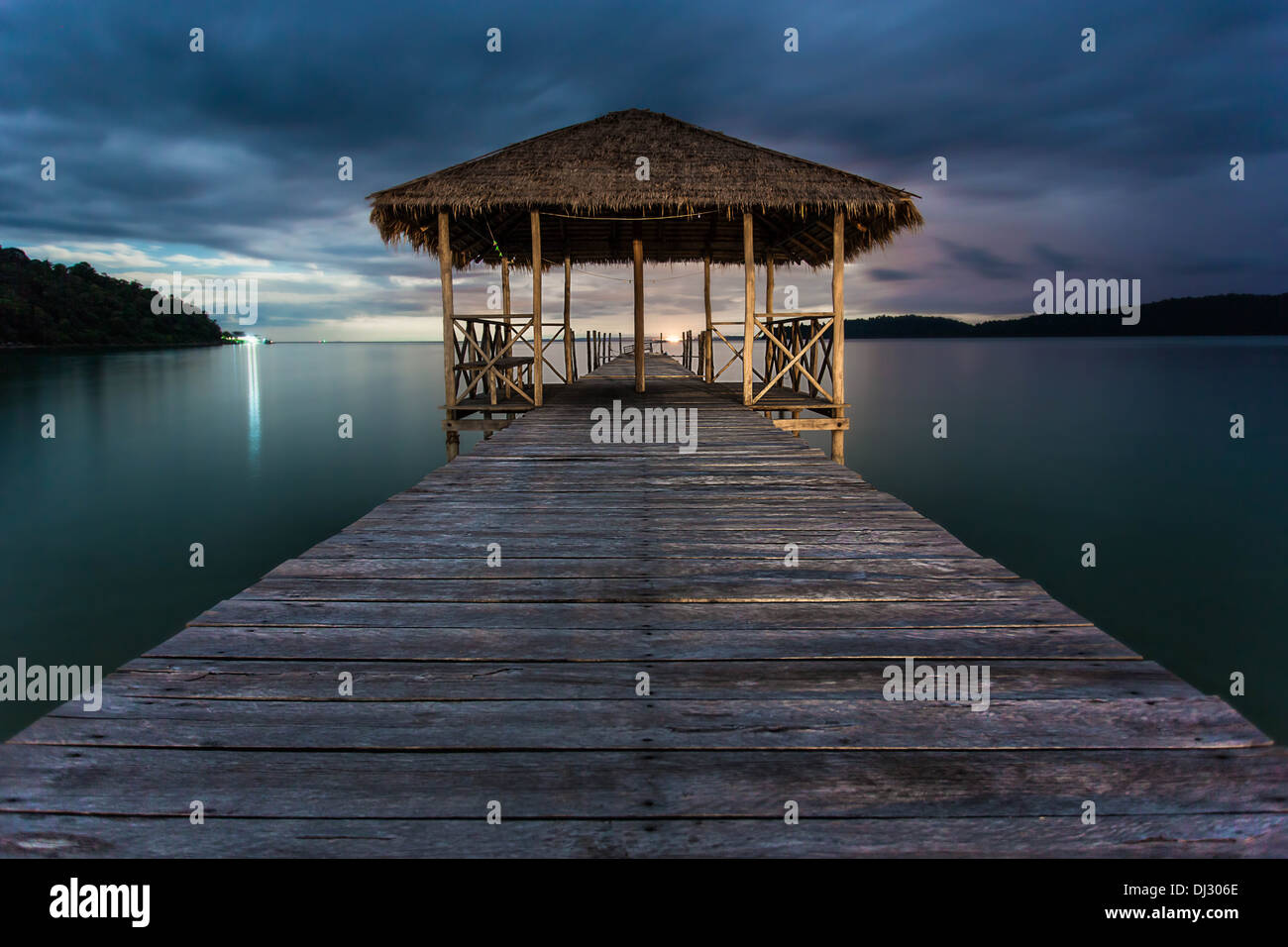 Jetée avec la pleine lune derrière les nuages dans la baie de Sarrasine, l'île de Koh Rong Samloem, au Cambodge. Banque D'Images