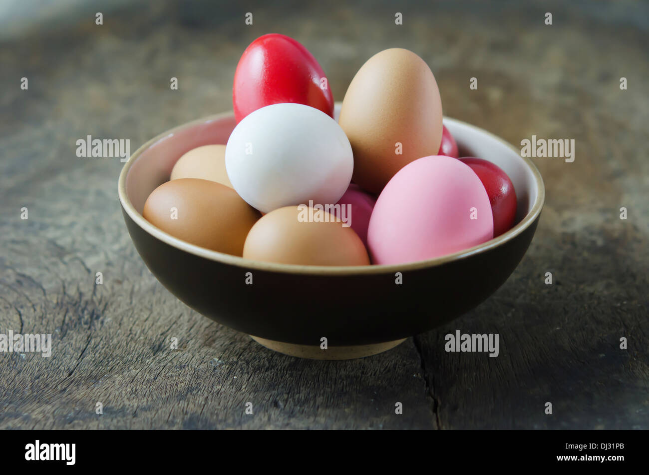 Des oeufs colorés dans un bol sur la table en bois Banque D'Images