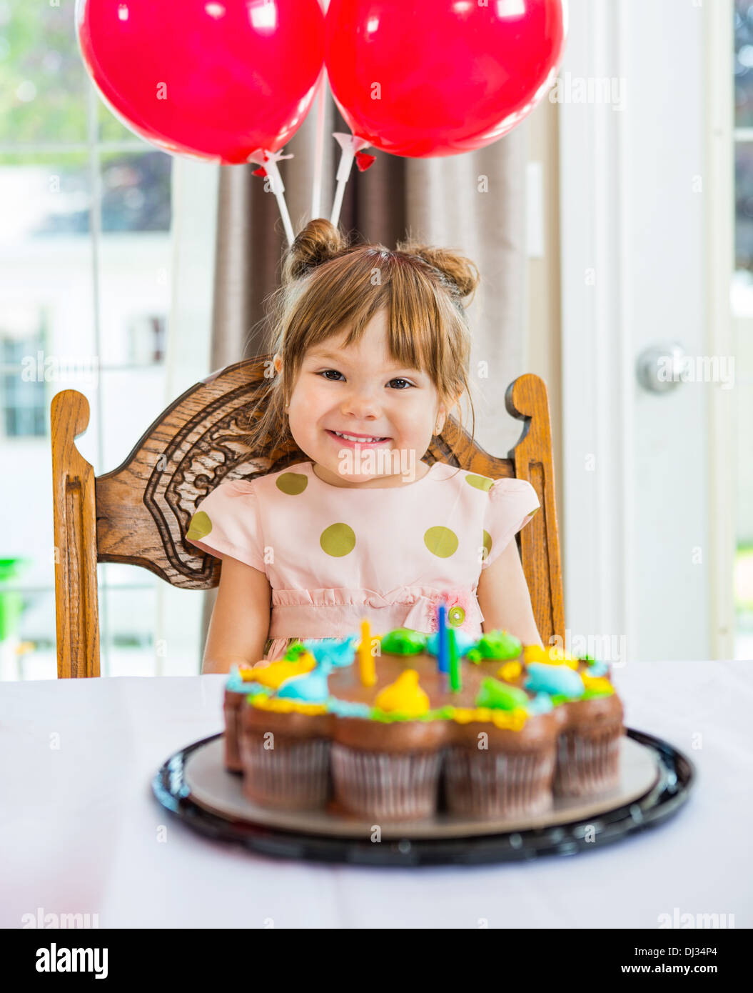 Happy Girl Sitting in front of Cake at Home Banque D'Images