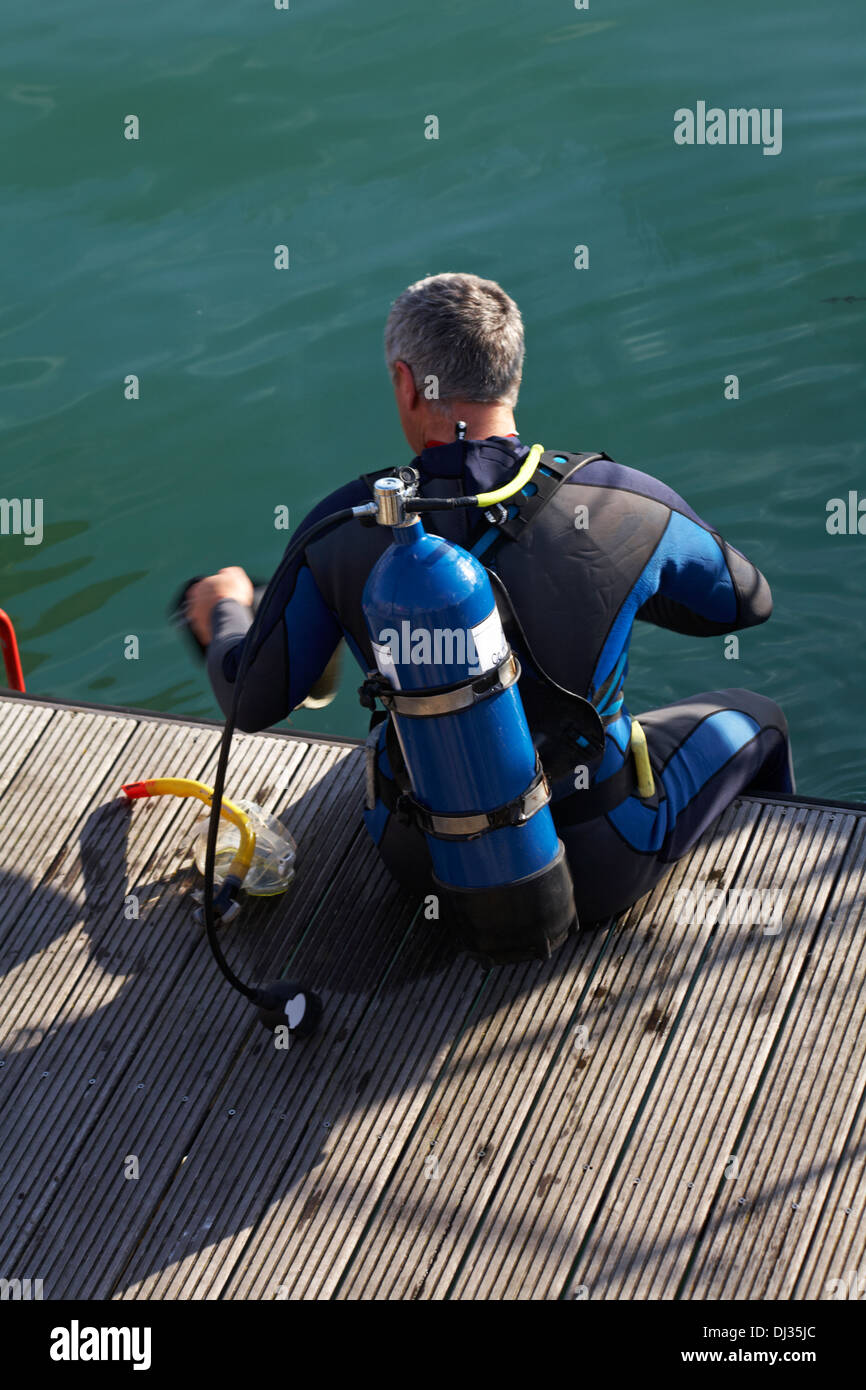 Scuba Diver sam sur ponton à Weymouth préparation de plongée en Novembre Banque D'Images