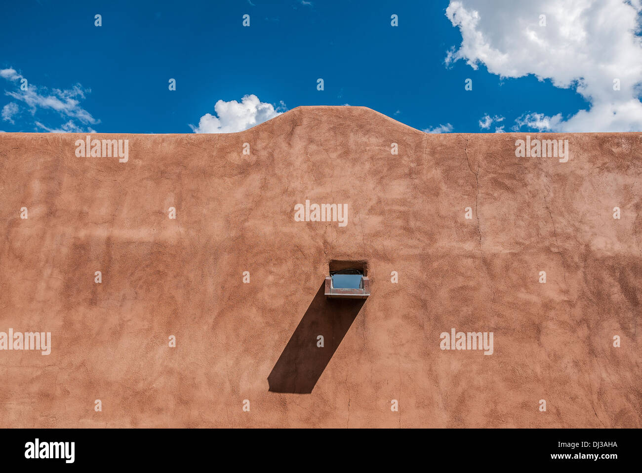 Un mur d'adobe traditionnelles avec canale pour le drainage de la pluie contre le ciel bleu à Santa Fe, Nouveau Mexique, USA. Banque D'Images
