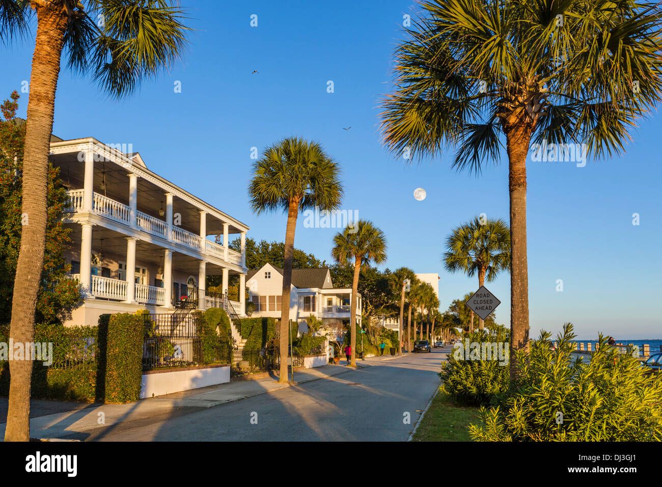 Les maisons historiques le long de la promenade Waterfront sur Murray Boulevard, éclairé par un soleil couchant, et avec la pleine lune, Charleston, Caroline du Sud, USA Banque D'Images