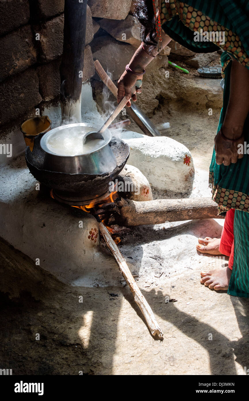 Femme indienne cuisson du riz sur un feu ouvert à l'extérieur de son village de l'Inde rurale accueil. L'Andhra Pradesh, Inde Banque D'Images