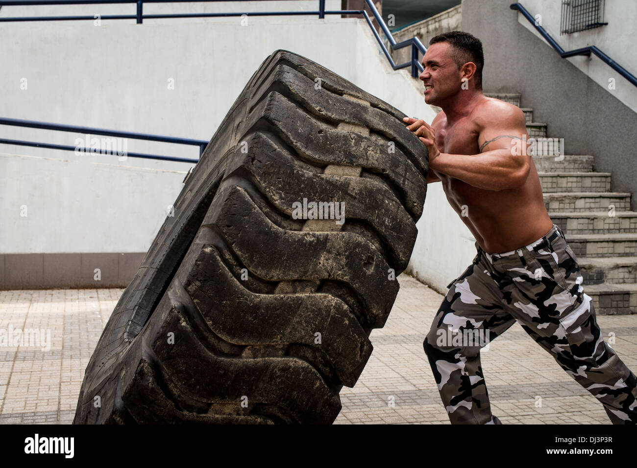 Un homme musclé qui participent à une séance d'entraînement en faisant monter un pneu flip Banque D'Images