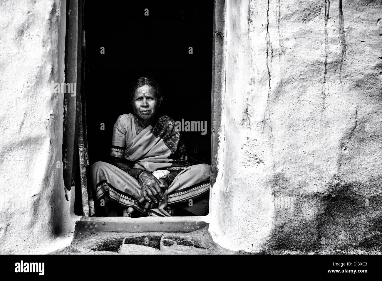 Personnes âgées Indian woman sitting in sa porte de son village à la maison. L'Andhra Pradesh, Inde. Noir et blanc. Banque D'Images