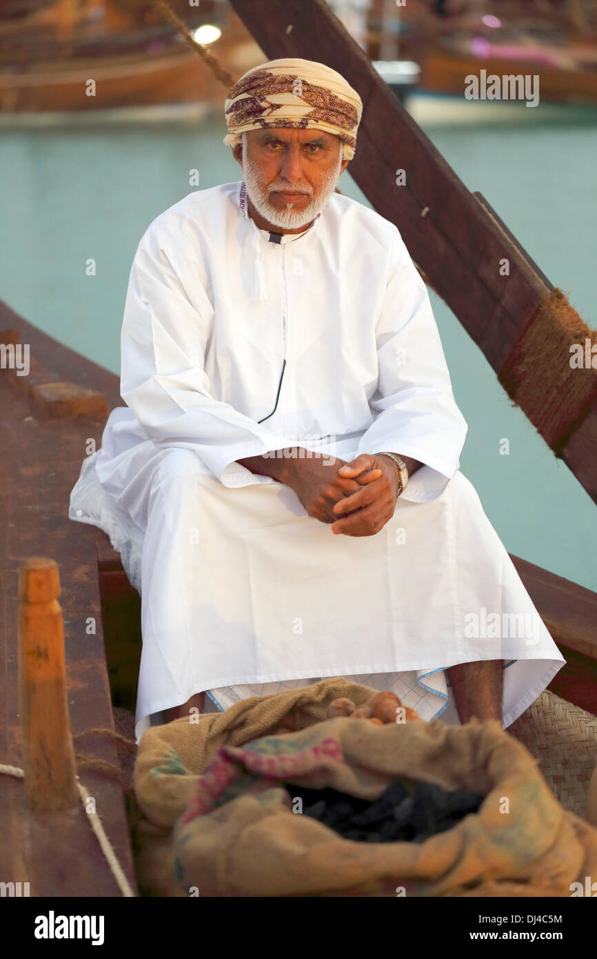 DOHA, QATAR - 21 novembre 2013 : un commerçant omanais se trouve à la proue de son bateau avec des sacs de charbon et de citrons séchés à ses pieds, à la 3ème Festival Dhow traditionnel en Katara cultural village, dans la région de la baie de l'ouest de la capitale du Qatar. Le désert unis aurait fortement appuyée sur seaborne fournitures d'aliments et d'autres marchandises dans le passé Crédit : Art du voyage/Alamy Live News Banque D'Images