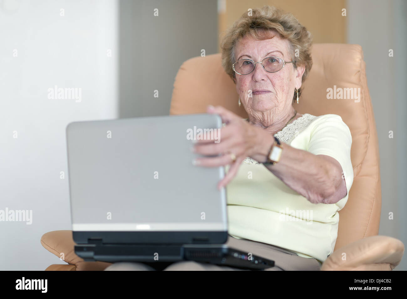 Le pensionné est assis sur une chaise avec un ordinateur portable Banque D'Images