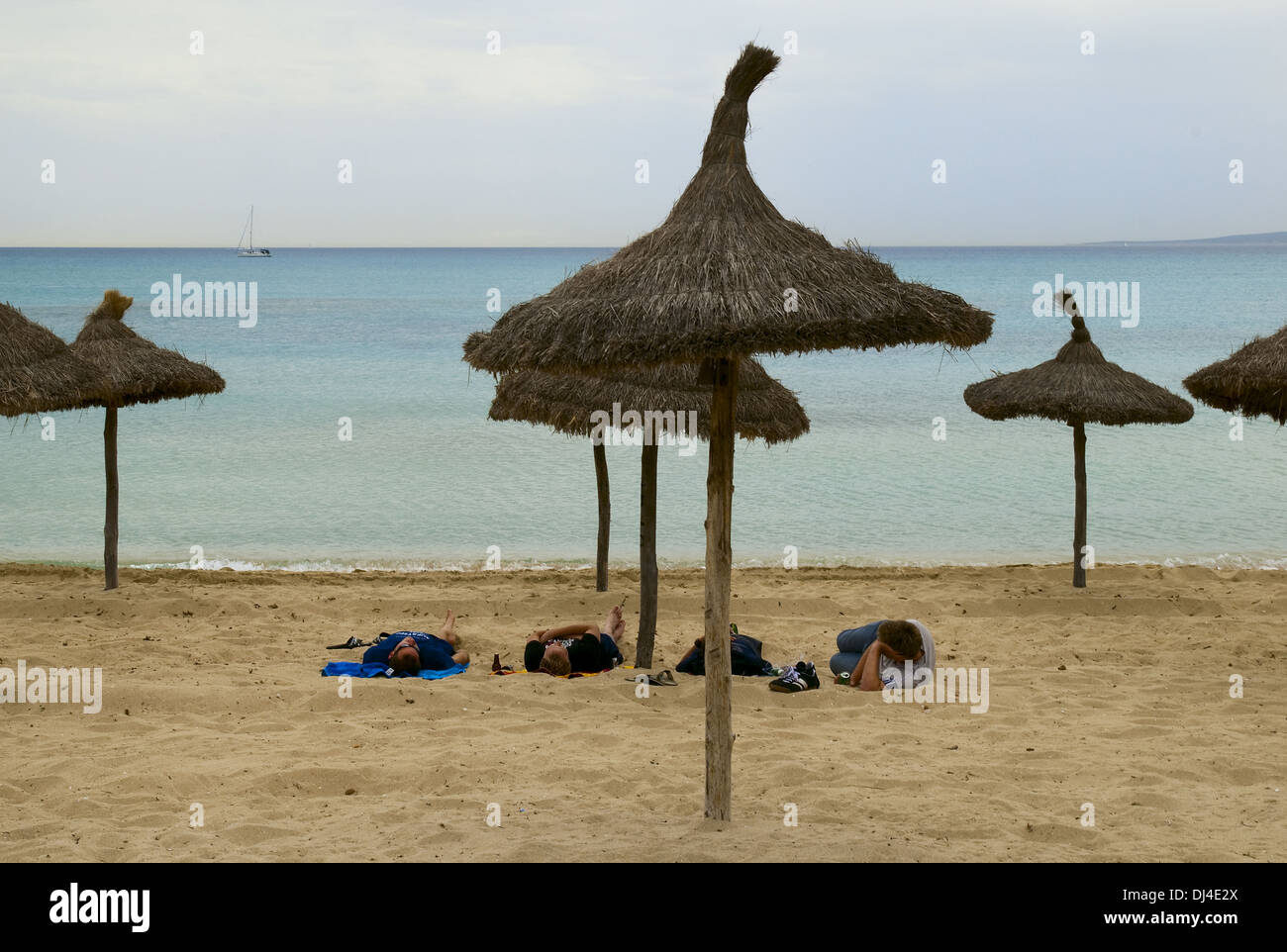 4 hommes couchés sur la plage de l'Arenal Banque D'Images