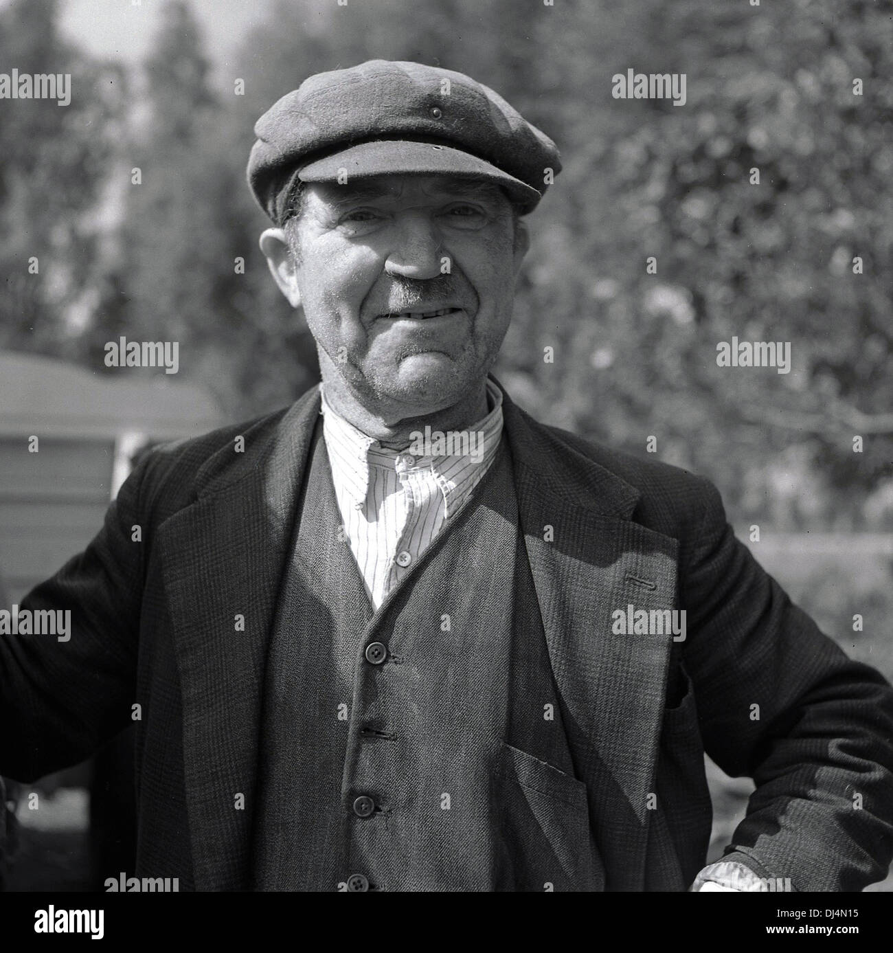 Photo historique, 1950s. Portrait d'un fier petit porteur ou d'un petit fermier dans les vêtements de l'époque et d'une casquette plate, debout sur son pays, Norfolk, Angleterre, Royaume-Uni. Banque D'Images