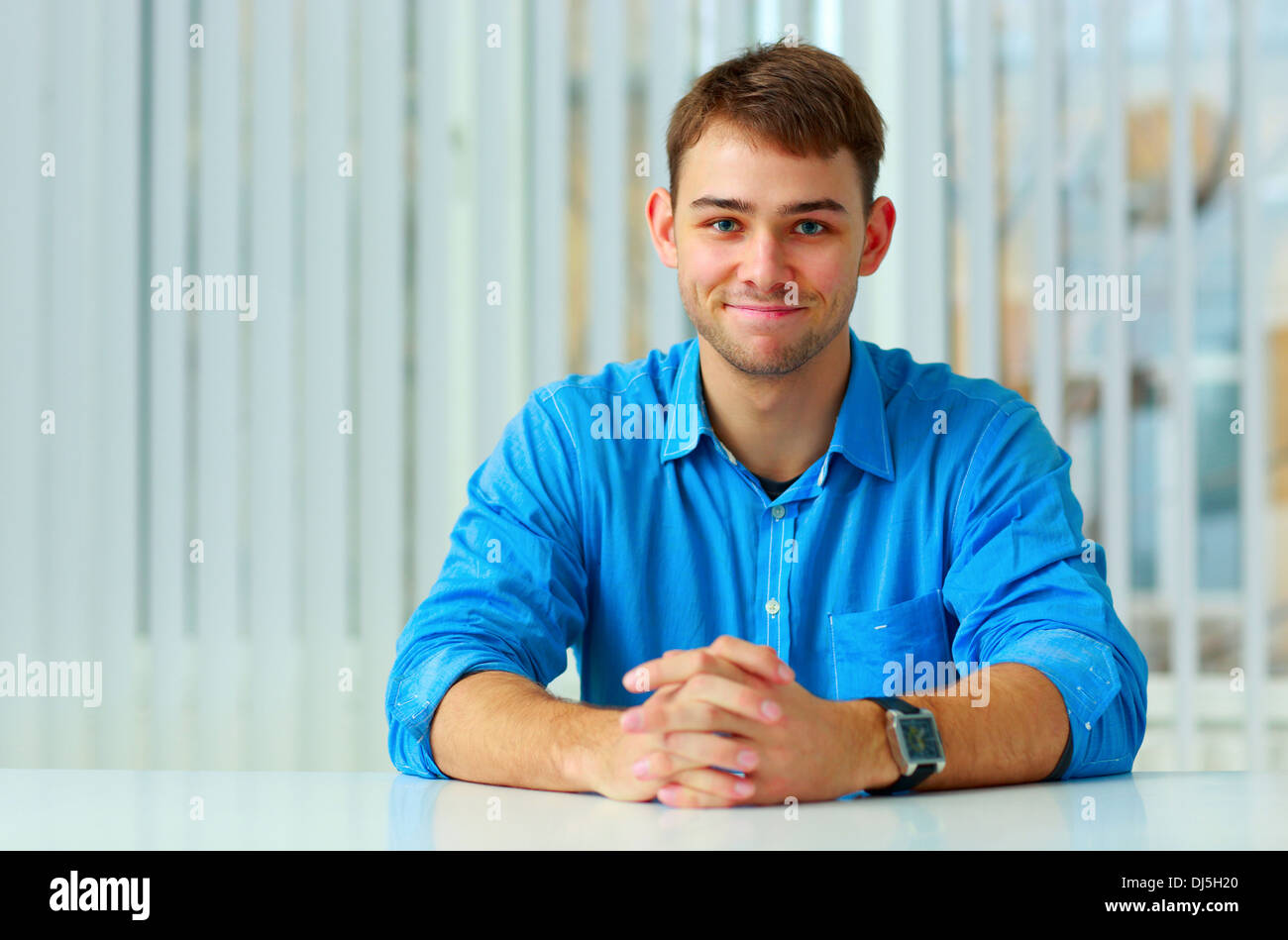 Young happy businessman sitting at table in office Banque D'Images