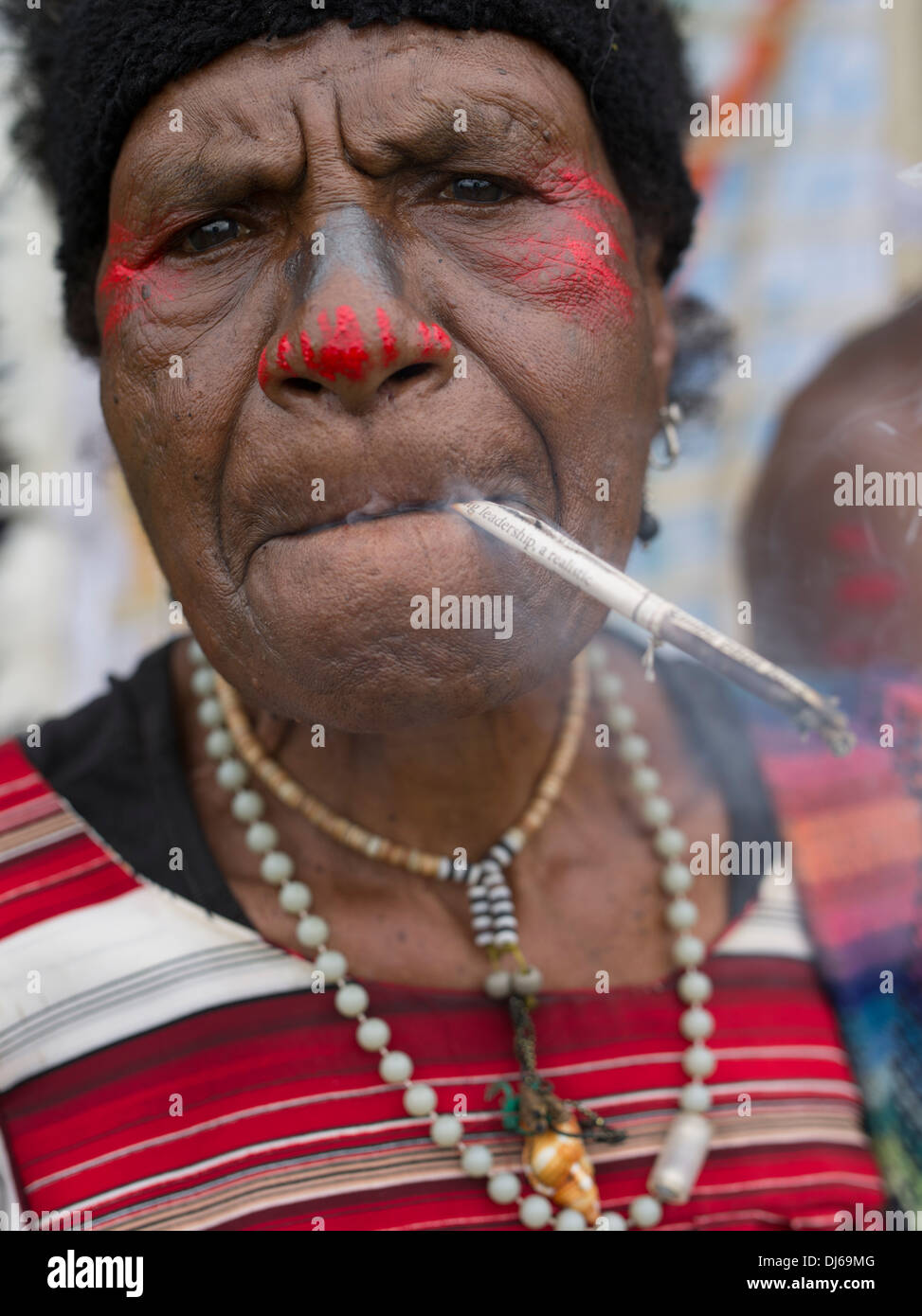 Femme âgée de Singsing, groupe Show Goroka, Papouasie-Nouvelle-Guinée fumeurs de cigarettes de tabac à la main Banque D'Images