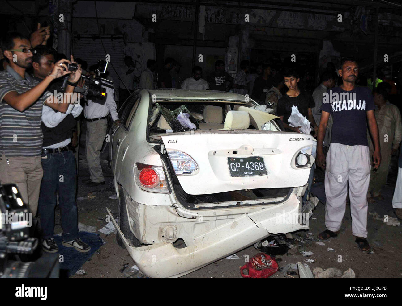 (131122) -- KARACHI, 22 novembre 2013 (Xinhua) -- les gens se sont réunis autour d'un véhicule détruit à l'explosion dans le sud de la ville de Karachi port pakistanais le 22 novembre, 2013. Au moins six personnes ont été tuées et 30 autres blessées lorsque deux explosions ont secoué la ville pakistanaise tard vendredi soir. (Xinhua/Masroor) Credit : Xinhua/Alamy Live News Banque D'Images