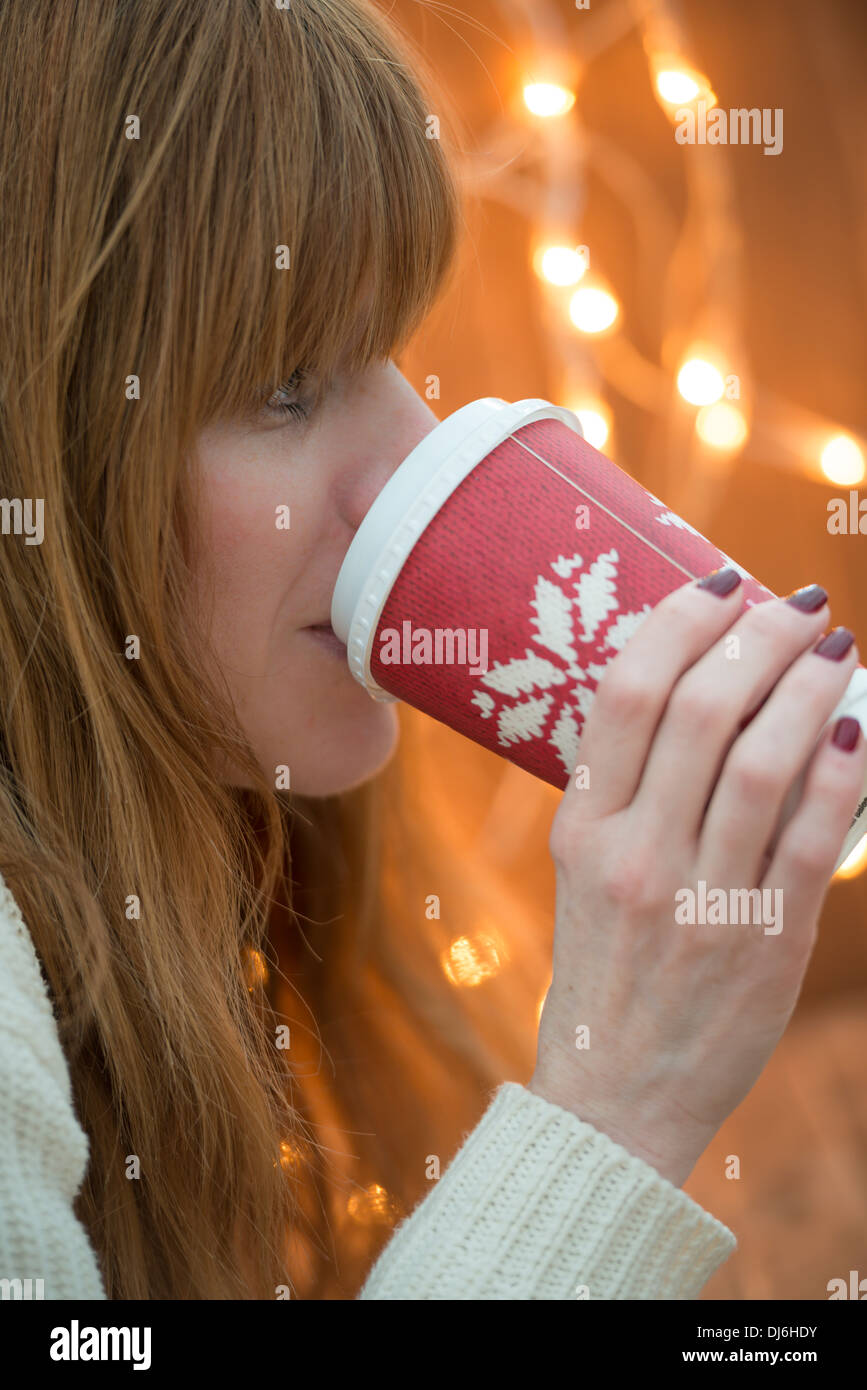 Femme buvant une boisson festive à l'époque de Noël Banque D'Images